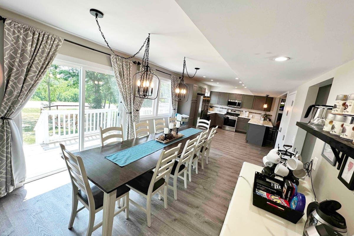 Long dining table by patio doors with a coffee and waffle bar in the foreground.