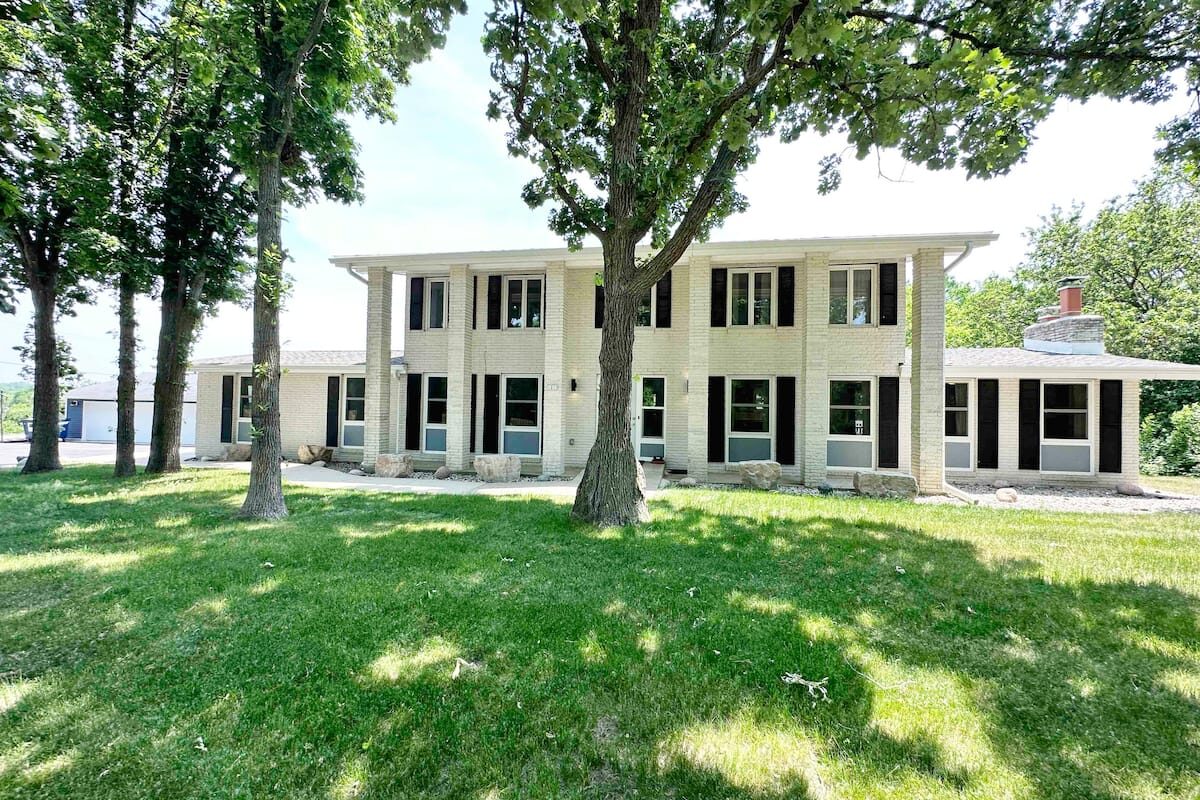 The cream-brick group house in Twin Lakes, set on a lawn under oak trees.
