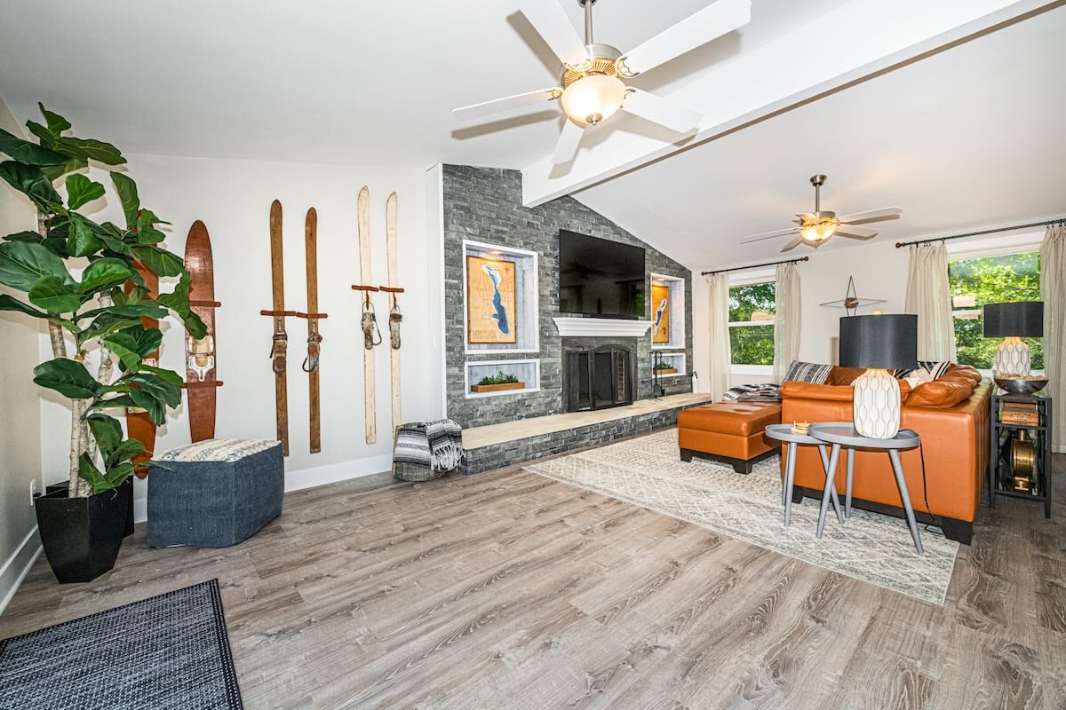 Living room with stone fireplace, vintage skis on the wall, and a leather sectional.