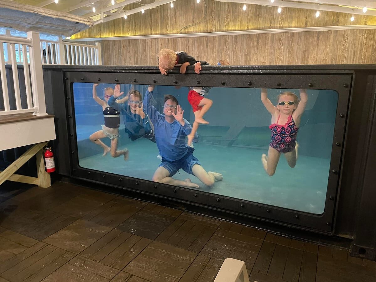 Family posing in the indoor pool behind the glass wall.